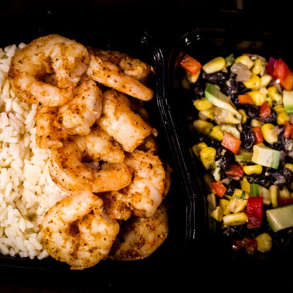 Seasoned shrimp and white rice next to a colorful corn, bean, and pepper salad.